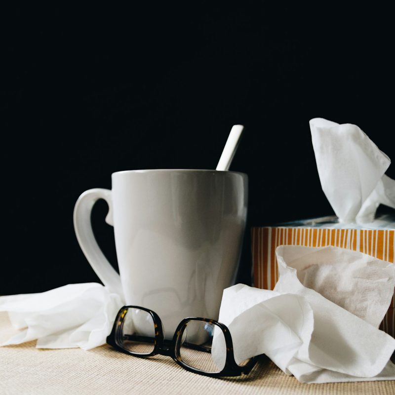 white ceramic mug on white table beside black eyeglasses